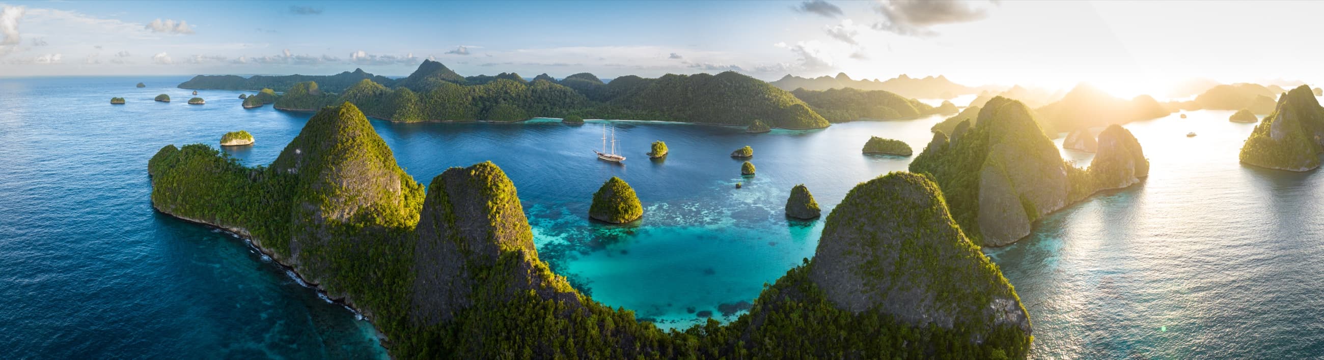 Raja Ampat archipelago at sunrise, expedition schooner at anchor